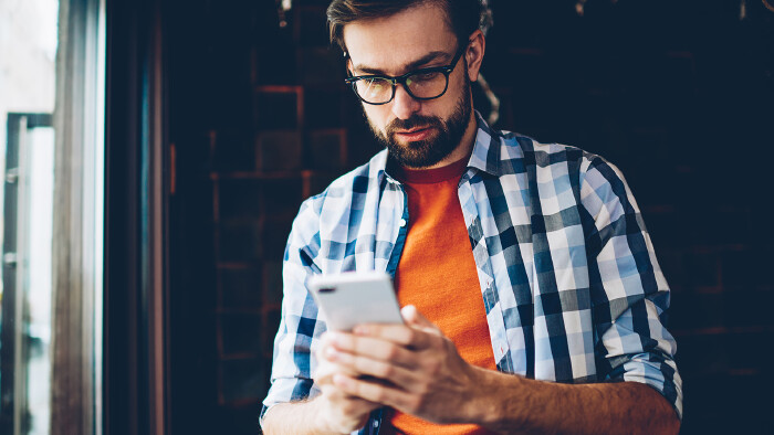 © BullRun, stock.adobe.com Junger Mann am Smartphone